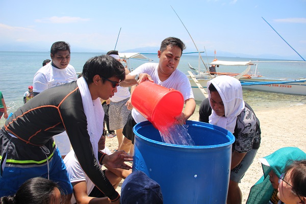 A group of people filling the drum with water